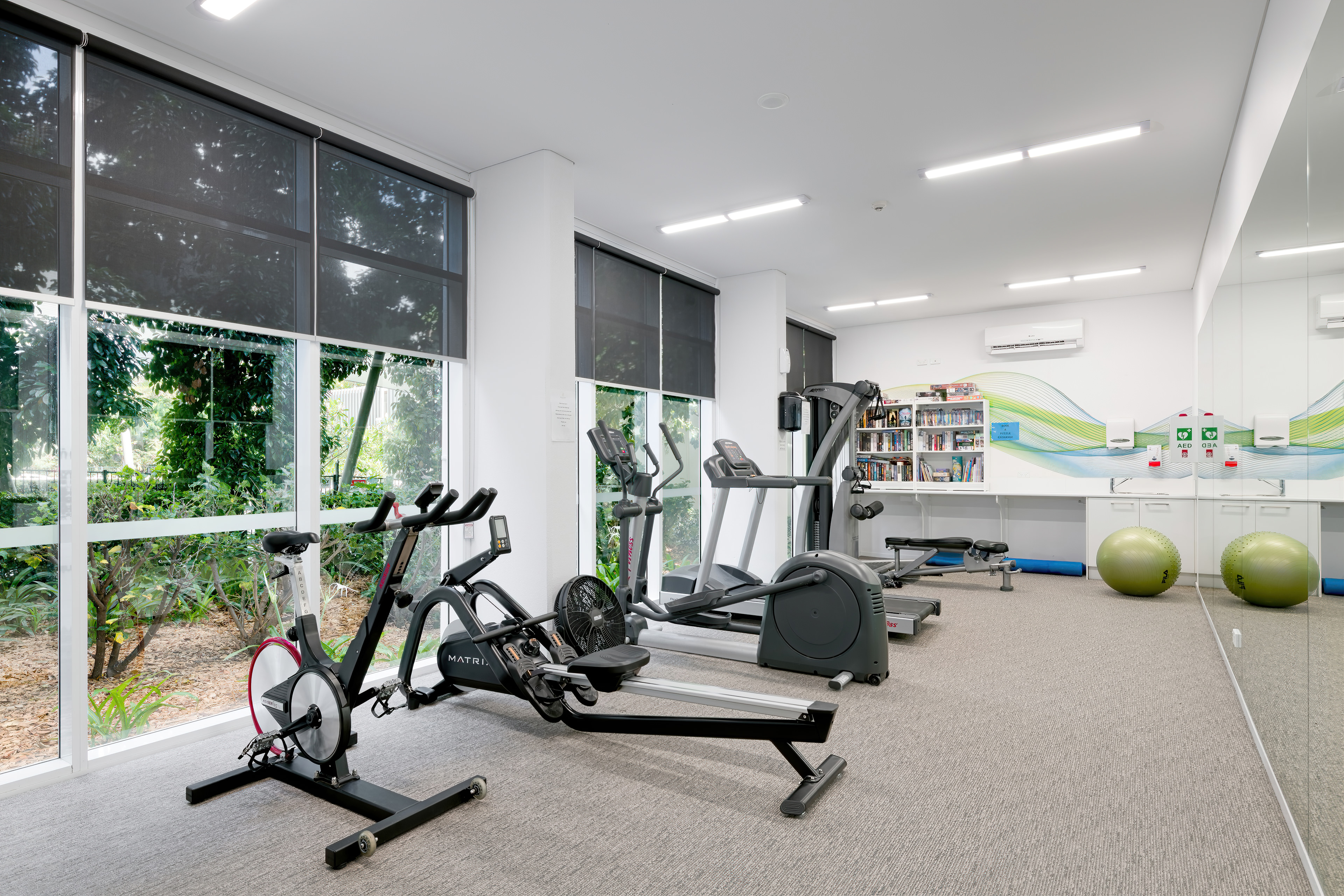 On-site gym with cardio equipment and floor-to-ceiling windows onto the garden